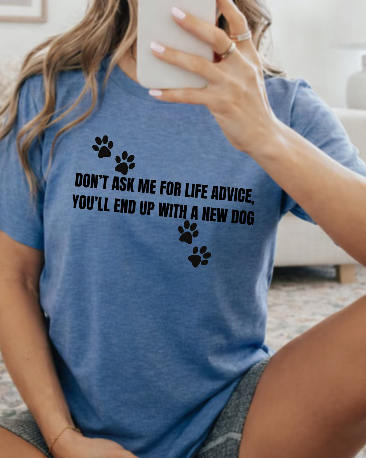 A woman taking a mirror selfie wearing a heather blue graphic t-shirt with black text that reads 'DON'T ASK ME FOR LIFE ADVICE, YOU'LL END UP WITH A NEW DOG' and black paw prints.