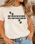 A woman wearing a white short-sleeve graphic t-shirt with black paw prints and the text 'DON'T ASK ME FOR LIFE ADVICE, YOU'LL END UP WITH A NEW DOG', paired with blue jeans.