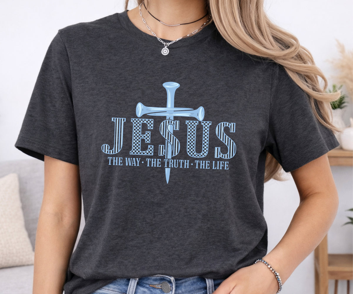 A woman wearing a dark heather gray t-shirt with a light blue graphic that reads 'JESUS THE WAY THE TRUTH THE LIFE' with a cross and dollar sign design.