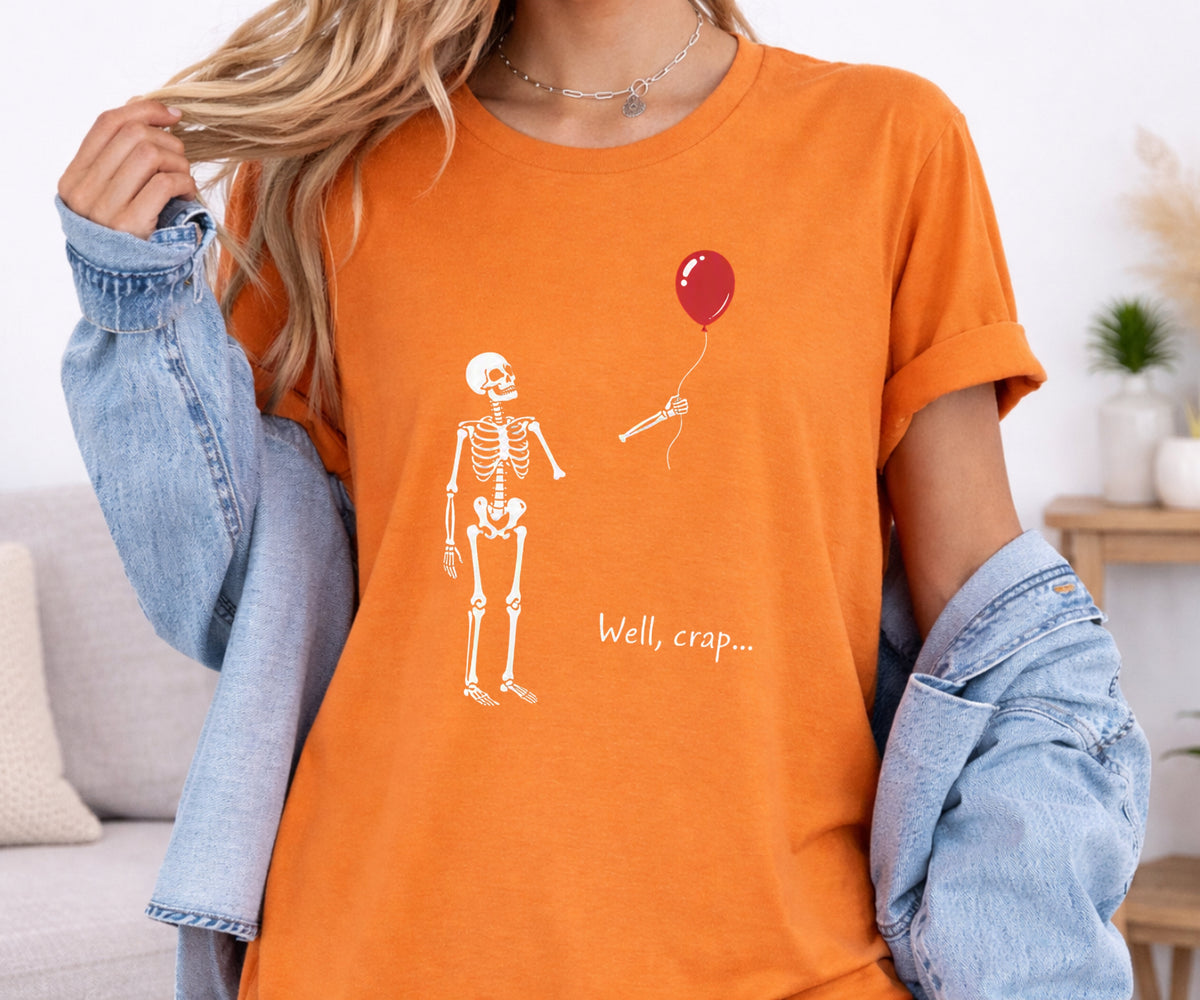 A woman wearing an orange graphic t-shirt with a white skeleton and a red balloon, styled with a light blue denim jacket draped off her shoulders.