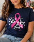 A woman wearing a navy blue graphic t-shirt with a pink breast cancer ribbon, a white cross, and the text 'with God all Things are Possible'.